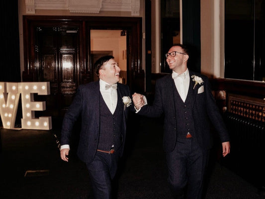 Two Grooms Celebrating their wedding in Navy Suits and Pale Green Bows